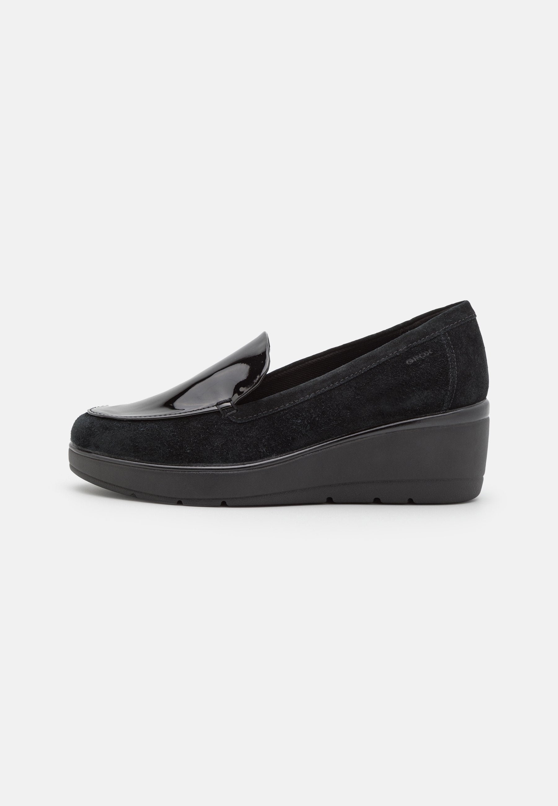Schwarze Slipper aus Wildleder mit glänzenden Lacklederakzenten. Merkmale sind ein Keilabsatz und ein abgerundetes Design. Leicht und flexibel.
