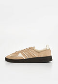 Beiger Wildleder-Sneaker mit weißen Akzenten, schwarzer Sohle, Schnürdesign und "Tommy Jeans"-Markenlogo an der Seite und auf der Sohle.
