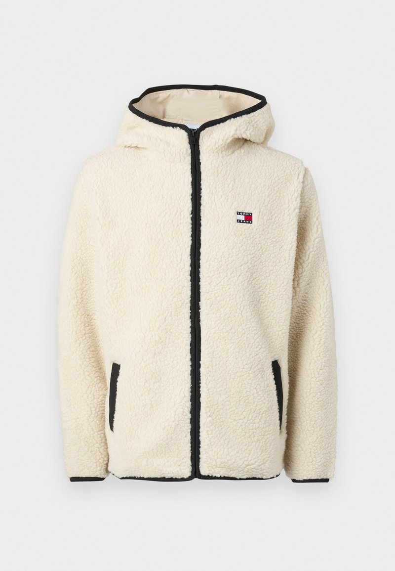 Cremfarbener Fleece-Hoodie mit Reißverschluss, schwarzem Besatz und Logopatch. Verfügt über Seitentaschen und einen weichen, strukturierten Stoff.