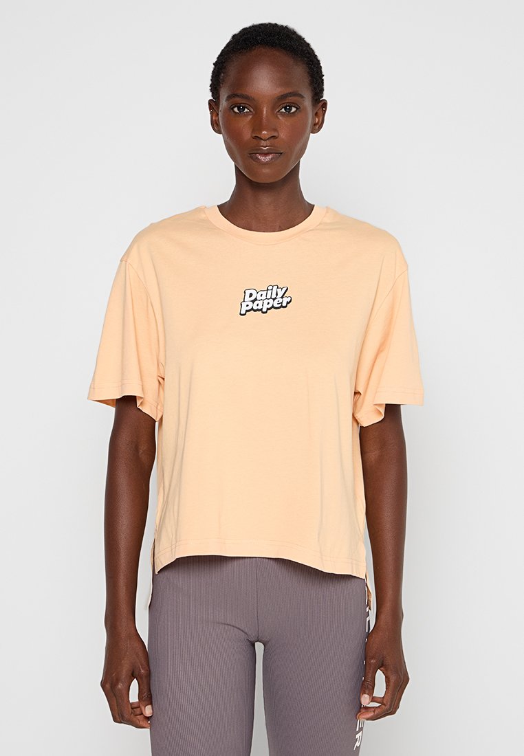 Pfirsichfarbene T-Shirt mit kurzen Ärmeln aus Baumwolle, mit einem runden Ausschnitt und einem schwarzen "Daily Paper"-Logo in der Mitte.