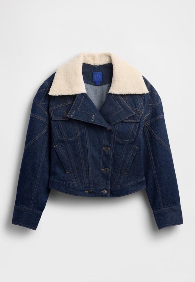 Dunkelblaue Jeansjacke mit cremefarbenem Sherpa-Kragen, figurbetontem Schnitt, Knopfverschluss und kontrastierenden Steppnähten. Verkürzte Länge mit Brusttaschen.