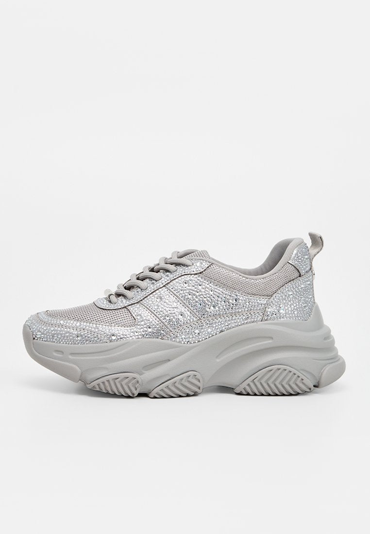 Silberne Glitzer-Sneaker mit einem strukturierten Mesh-Obermaterial, dicker grauer Sohle, gepolstertem Kragen und drei dekorativen Streifen an der Seite.