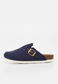 Marineblauer Slipper mit Messingschnallenriemen, Korkfußbett und weißer, strukturierter Sohle, seitlich auf weißem Hintergrund dargestellt.