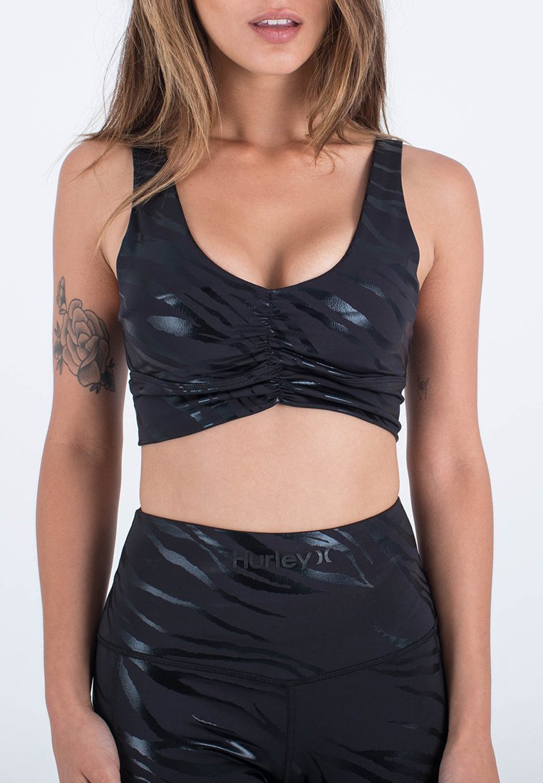 Schwarzes athletisches Crop-Top mit glänzendem, strukturiertem Zebramuster, ausgestattet mit einem U-Boot-Ausschnitt und gerafften Details an der Vorderseite.