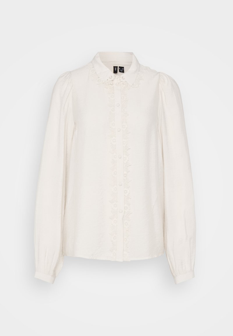 Weiße Bluse mit langen Ärmeln und kragenförmigem Halsauschnitt, strukturierter Stoff, zentrale Knopfverschluss und Blumenstickerei entlang der Vorderseite.