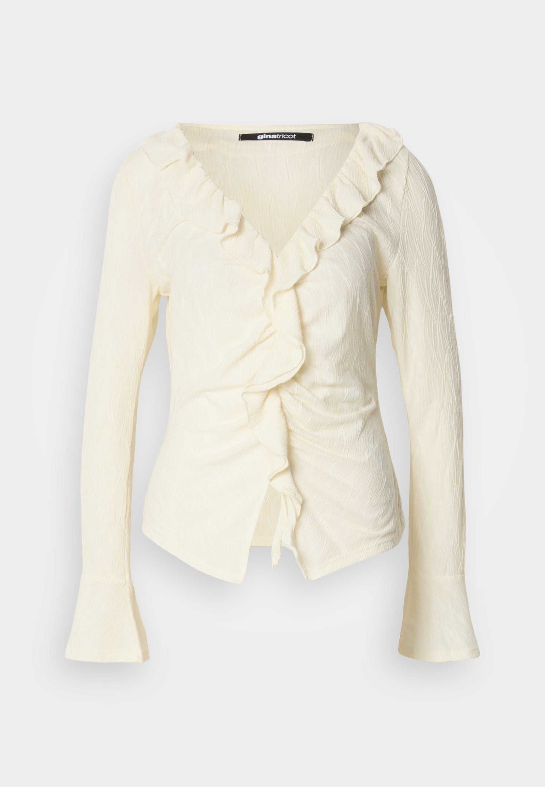 Cremfarbene Bluse mit langen Ärmeln, V-Ausschnitt, Rüschendetail, geraffter Seite und Glockenärmel. Hergestellt aus leichtem, strukturiertem Stoff.