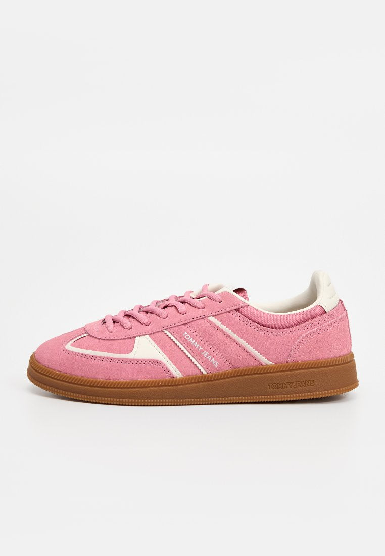 Pinkfarbener Sneaker aus Wildleder mit niedrigem Schaft, weißen Akzenten, brauner Gummisohle, Schnürdesign und "Tommy Jeans"-Logo seitlich und auf der Sohle.