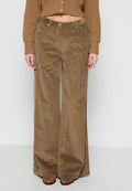 Braune Cordhose mit weitem Bein und strukturierter Oberfläche, versehen mit seitlichen Taschen und einem Knopfverschluss, kombiniert mit einem kurzen Top.