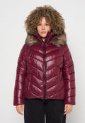 Bordeauxrote Steppjacke mit Chevron-Muster, Reißverschluss und einem mit Fell gefütterten Kapuzen. Glatte, glänzende Textur, entworfen für Wärme und Komfort.