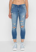 Helle blaue Jeans im Skinny Fit mit mehreren Distressed-Details, einem cropped Saum und Fünf-Taschen-Stil, kombiniert mit weißen Sneakers.