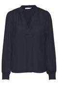 Dunkelblaue Bluse mit V-Ausschnitt, Raffungen an den Schultern und langen Ärmeln mit elastischen Bündchen. Hergestellt aus glattem Stoff.