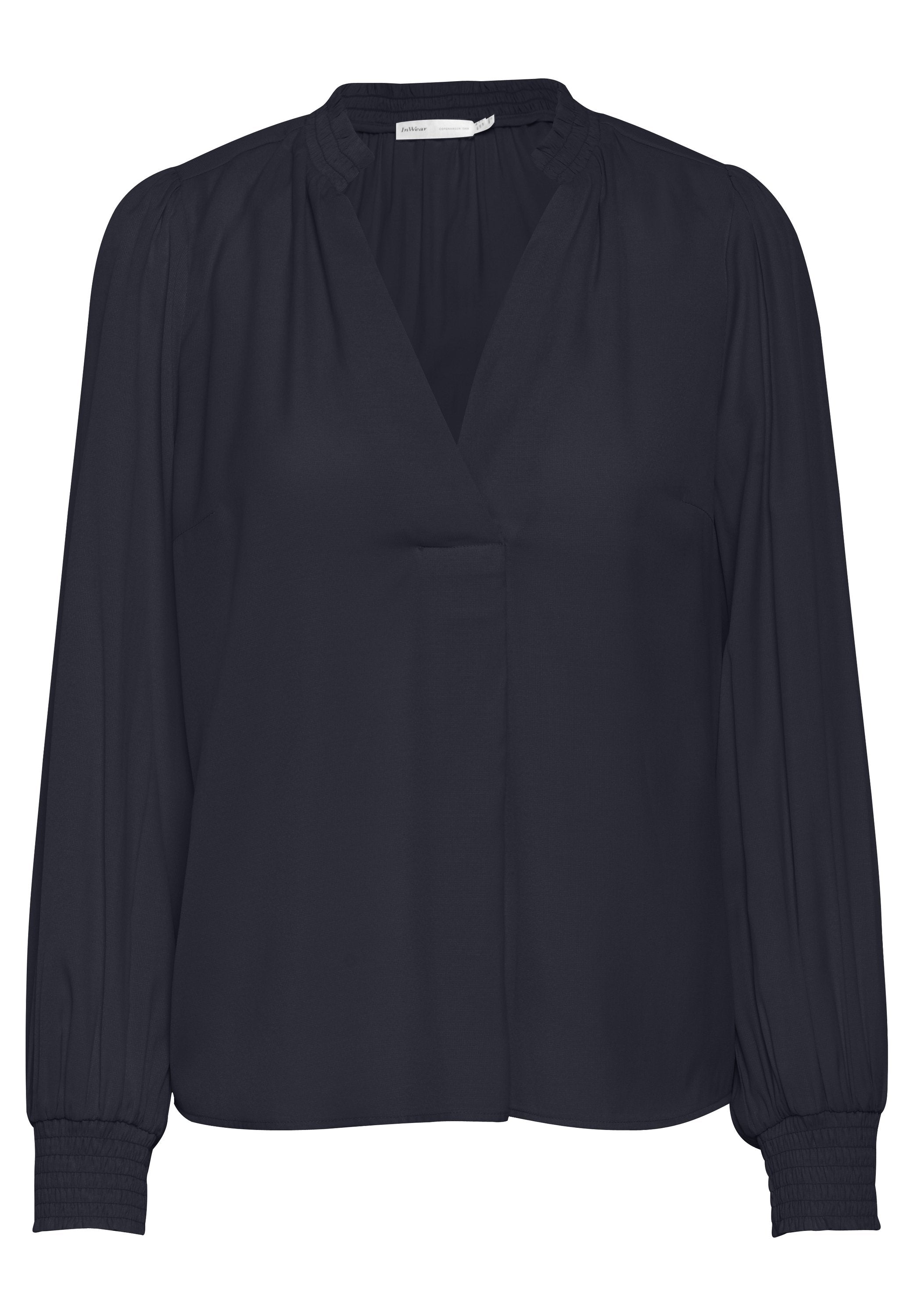 Dunkelblaue Bluse mit V-Ausschnitt, Raffungen an den Schultern und langen Ärmeln mit elastischen Bündchen. Hergestellt aus glattem Stoff.