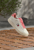 Weißer Sneaker mit rosa Akzenten, mit glattem Lederobermaterial, rosa Schnürsenkeln und einem kleinen Logopatch an der Seite.
