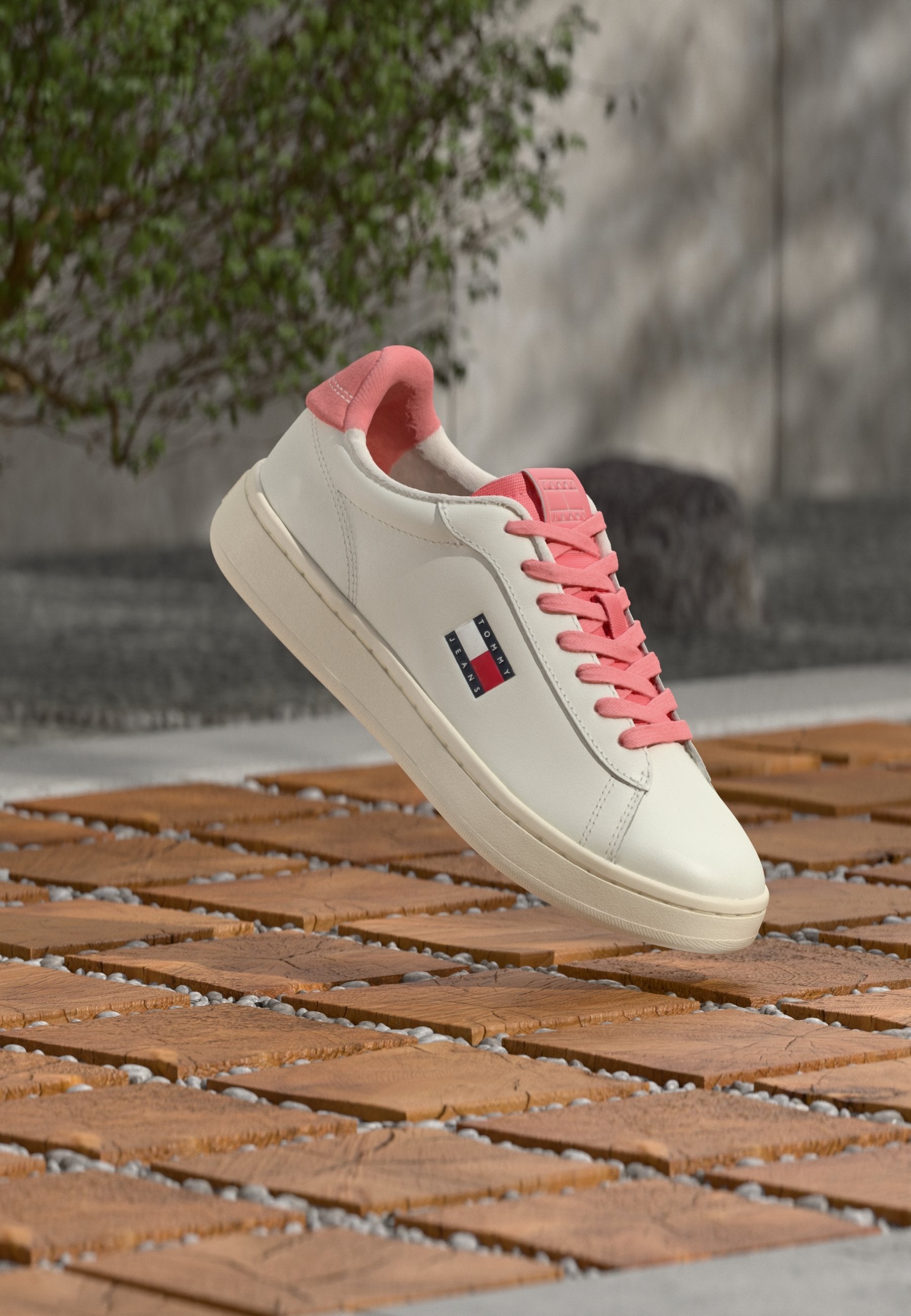 Weißer Sneaker mit rosa Akzenten, mit glattem Lederobermaterial, rosa Schnürsenkeln und einem kleinen Logopatch an der Seite.