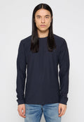 Marineblaues Langarmshirt aus strukturiertem Stoff, mit Rundhalsausschnitt und schmalen Ärmeln, kombiniert mit hellblauen, stark ausgewaschenen Jeans.