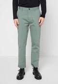 Hellgrüne Baumwollhose mit geradem Schnitt, Bund mit Knopfverschluss und vier Taschen. Getragen mit schwarzen Schuhen.
