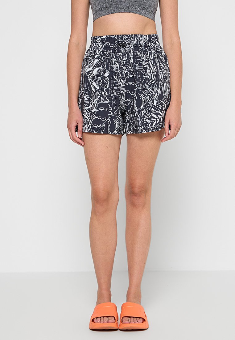 Marineblaue Shorts mit einem weißen botanischen Muster, elastischem Bund und zwei seitlichen Taschen. getragen mit orangefarbenen Flachsandalen.