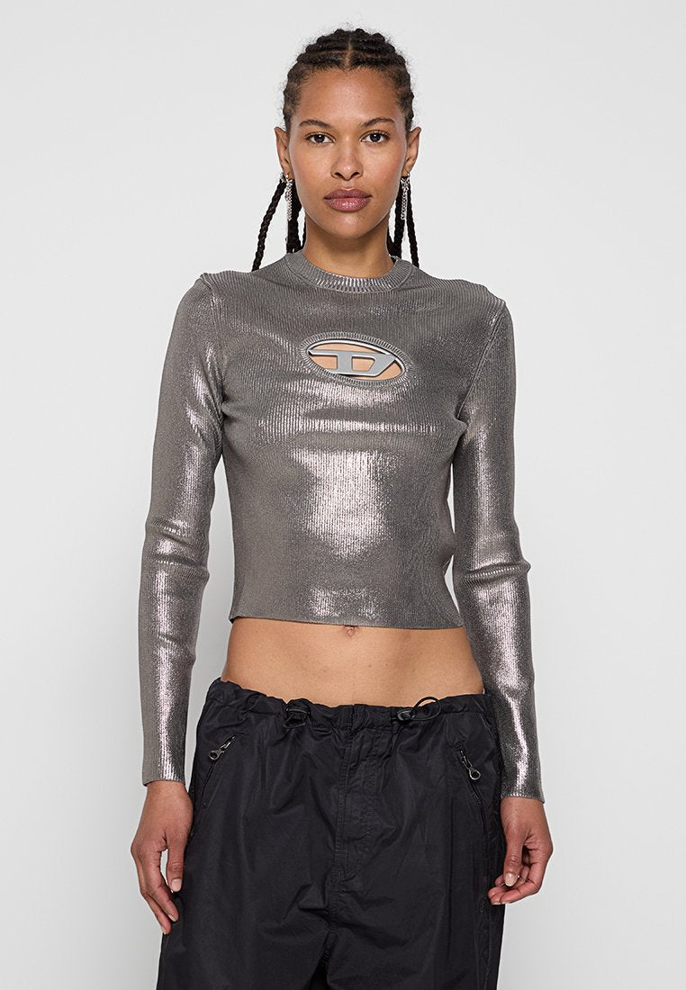 Metallisch graues, langärmeliges, cropped Oberteil mit einem zentralen Ausschnitt und geripptem Textil. Kombiniert mit schwarzen Jogginghosen mit Zugkordel.