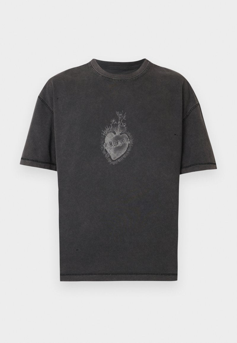 Schwarzes Baumwoll-T-Shirt mit lockerem Sitz, das ein grafisches Design eines Herzens mit Blumen und Totenköpfen in der Mitte zeigt. Sichtbare Nahtdetails.