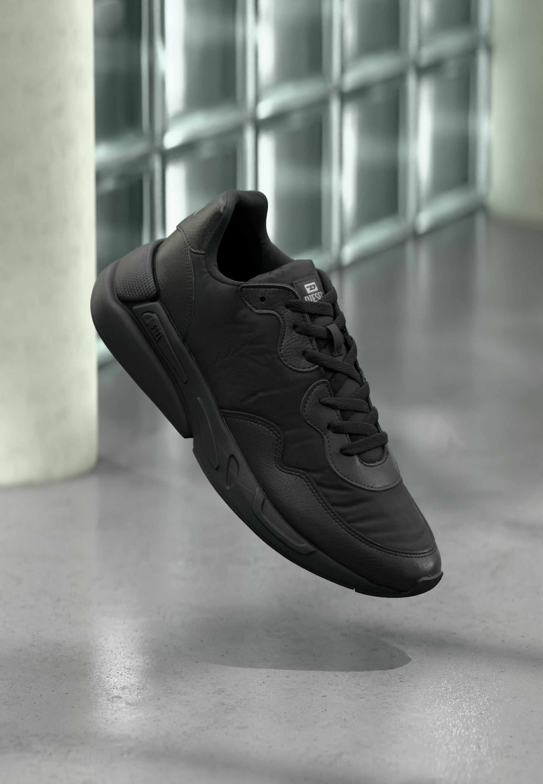 Schwarzer Sportschuh mit Lederoberfläche, rundem Zehenbereich und strukturierten Akzenten. Verfügt über eine Schnürung und eine gepolsterte Sohle für Komfort.