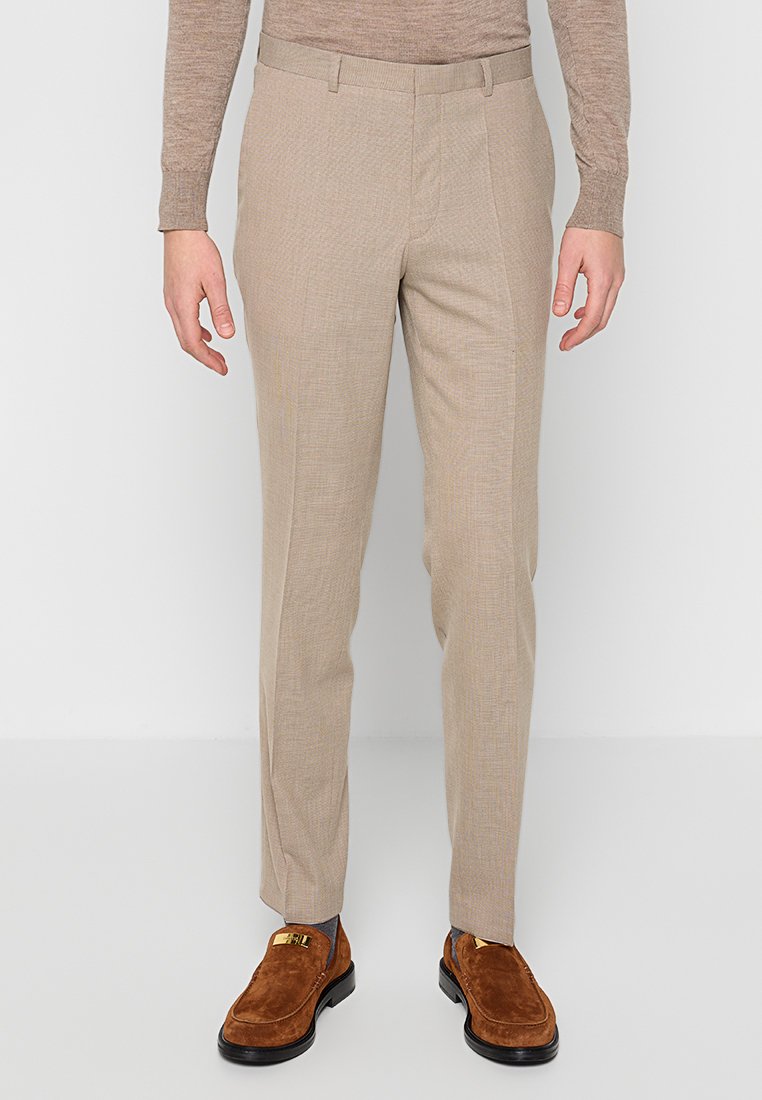 Beige, maßgeschneiderte Hose mit einem dezenten strukturierten Muster, ausgestattet mit einem glatten Bund und Seitentaschen, kombiniert mit braunen Wildlederschuhen.