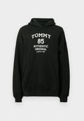 Schwarzer Hoodie aus weichem Stoff mit Kängurutasche. Auf der Vorderseite befindet sich weißer Text: "TOMMY 85 AUTHENTIC ORIGINAL seit 1985".