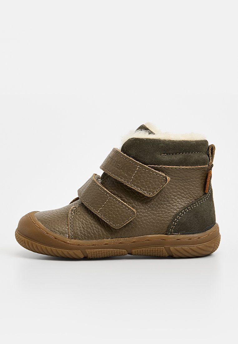 Braune Leder-Stiefelette mit zwei Klettverschlüssen, ausgestattet mit einem weichen cremefarbenen Futter und einer Gummisohle. Enthält Wildlederakzente auf der Rückseite.