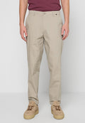 Beige Chinos aus Baumwolle mit geradem Schnitt, ausgestattet mit Vordertaschen und einem Knopfverschluss, kombiniert mit beigen Sneakern.