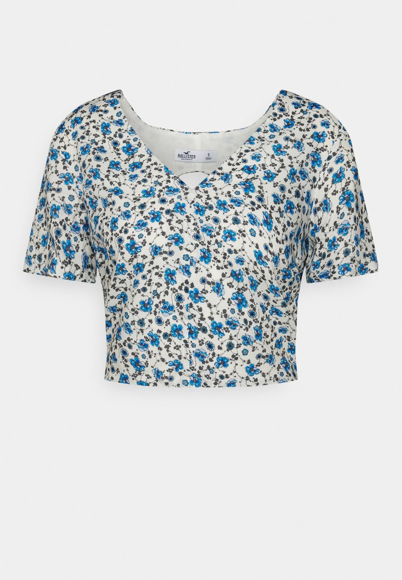 Gekürztes V-Ausschnitt-T-Shirt aus leichtem Stoff, mit einem floralen Muster in Blau und Schwarz auf einem weißen Hintergrund, mit kurzen Ärmeln.