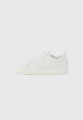Weißer Sneaker mit niedrigem Schaft, Schnürung vorne und elfenbeinfarbener Gummisohle, von der Innenseite auf hellem grauem Hintergrund gezeigt.
