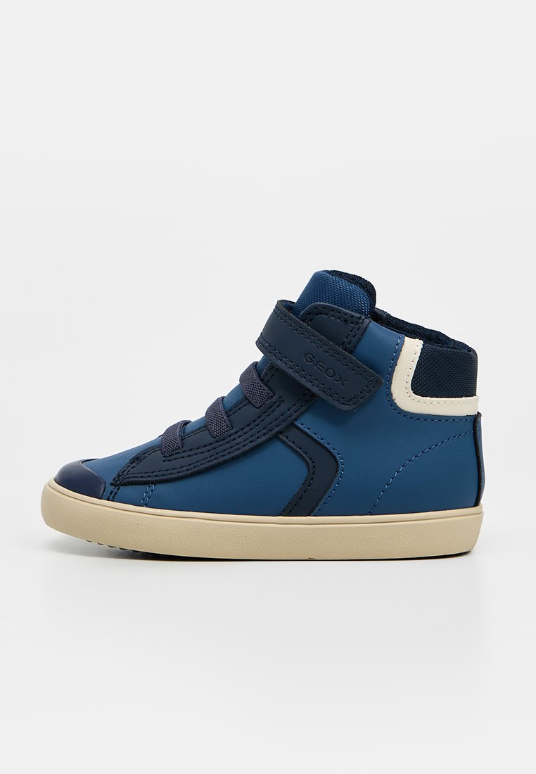 Blauer High-Top-Kinderschuh mit marineblauen Schnürsenkeln, beiger Sohle, Klettverschluss und weißem Akzent an der Ferse.