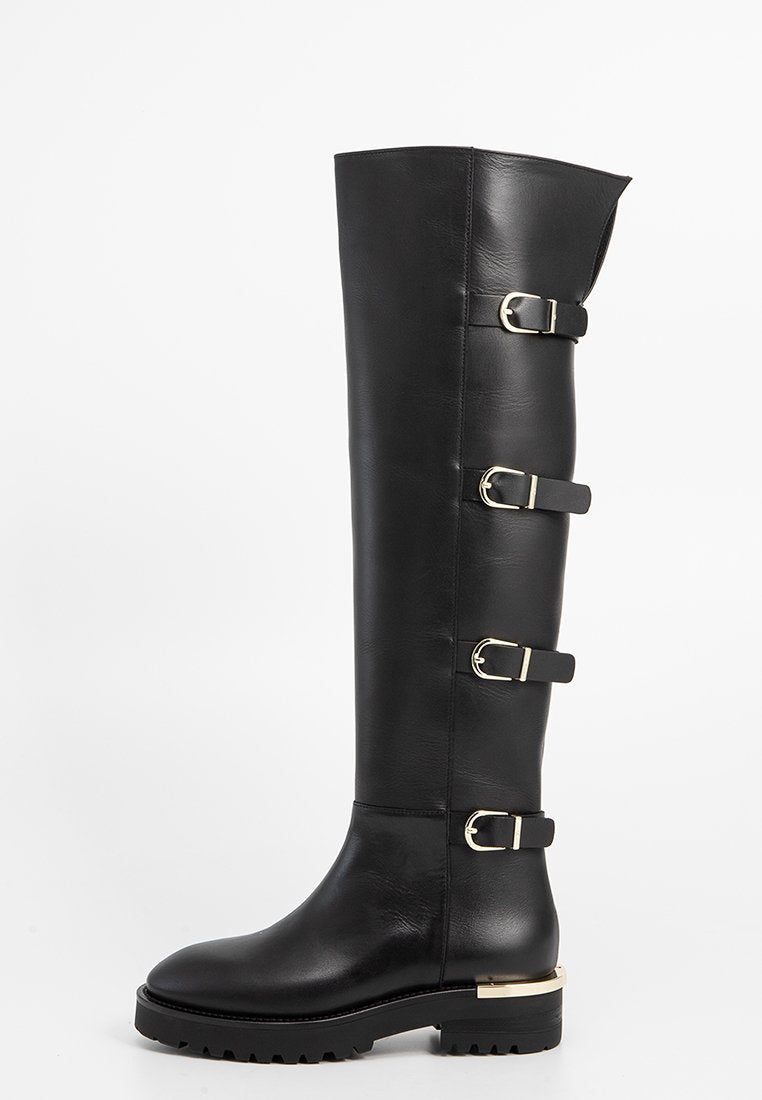 Schwarze kniehohe Lederstiefel mit vier goldenen Schnallenriegeln und einer klobigen Sohle mit goldenen Absatzdetails, seitlich betrachtet.