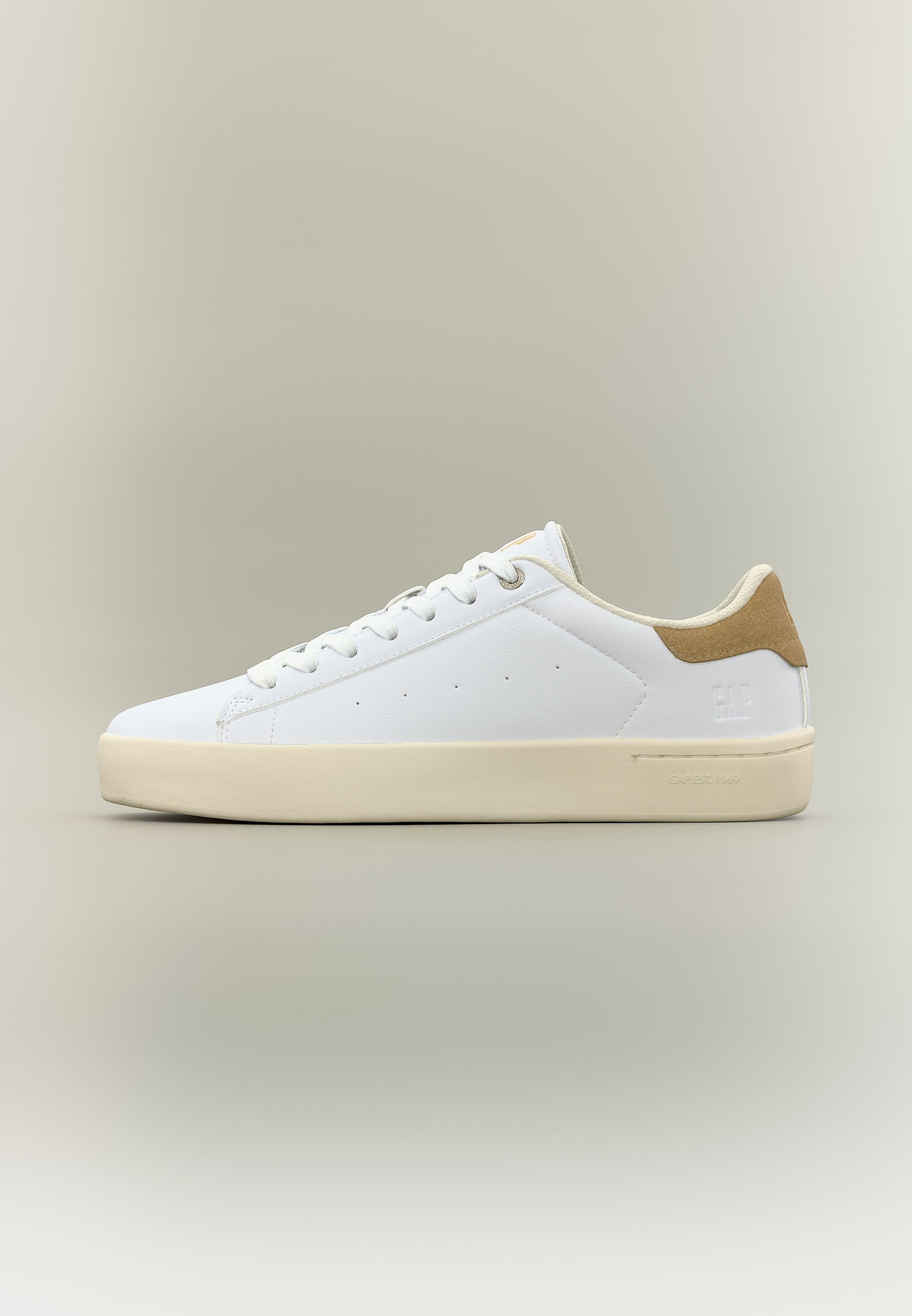 Weißer Sneaker mit niedrigem Schaft, beigefarbener Sohle und hellbraunem Veloursleder-Fersenpatch, Schnürdesign und minimalen Perforationsdetails an der Seite.