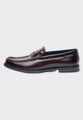 Braune Lederloafers mit glänzendem Finish, dekorativer Naht und einem kleinen Akzent am Riemen. Flache Gummisohle für Komfort.