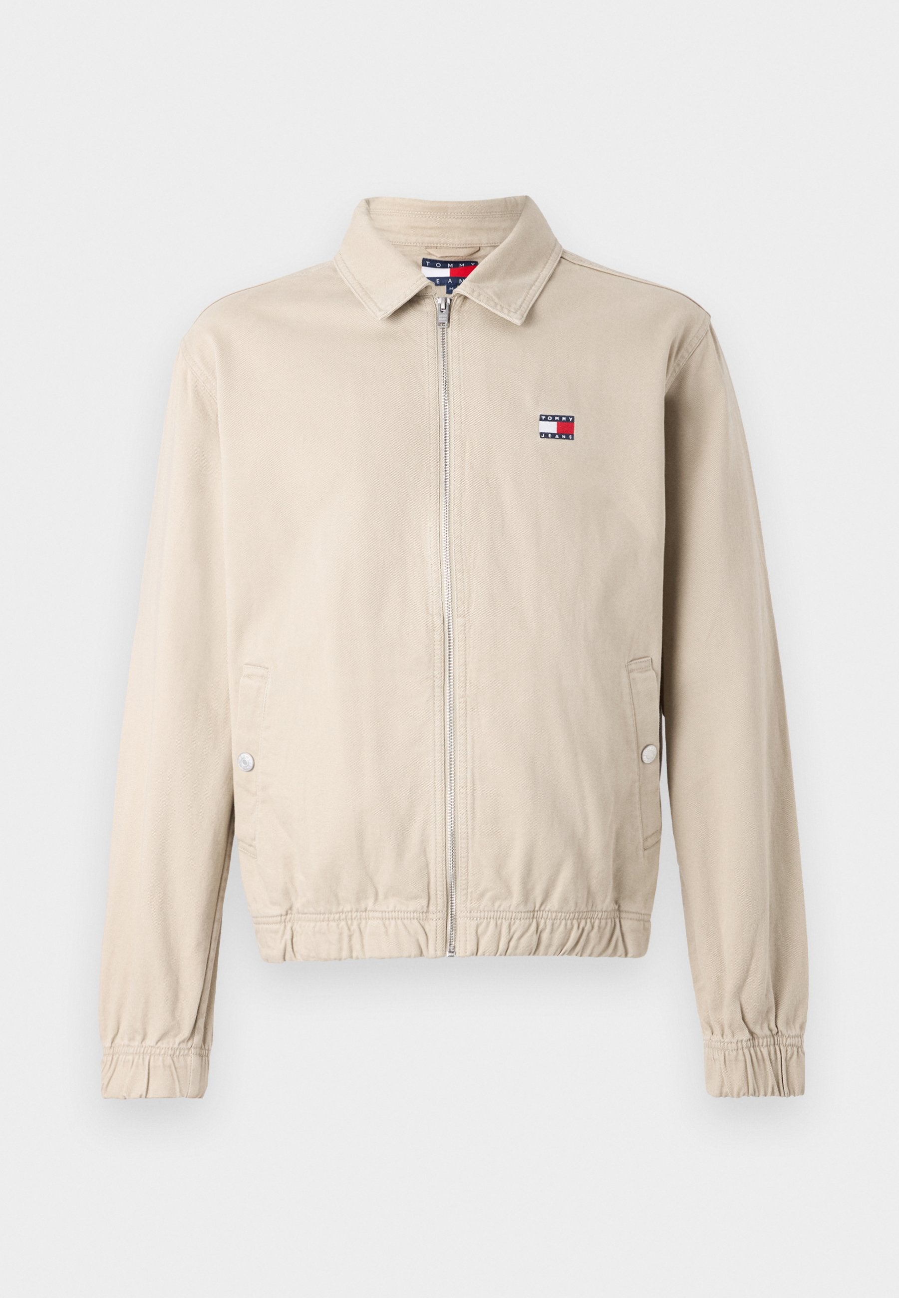 Khakifarbene Jacke mit Reißverschluss, Kragen, elastischen Bündchen und tailliertem Schnitt. Mit kleinem Logo auf der linken Brust. Glatte Stoffstruktur.
