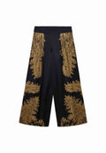 Schwarze Culottes mit goldfarbener Paisleymusterung an den Seiten, featuring ein weiter Beinform und elastischem Taillenbund. Glatte Textur.