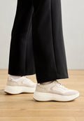 Sneaker aus einer Kombination von hellrosa und beige Materialien, mit einem strukturierten Fersenbereich, runder Zehenpartie und dicker weißer Sohle.