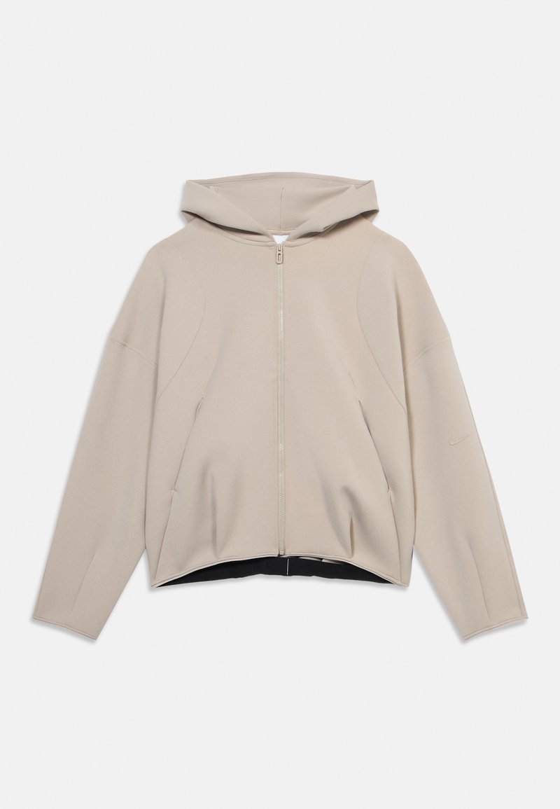 Hellbeige Kapuzenpullover mit Reißverschluss, langen Ärmeln und leicht geschwungenem Saum, flach auf weißem Hintergrund dargestellt.