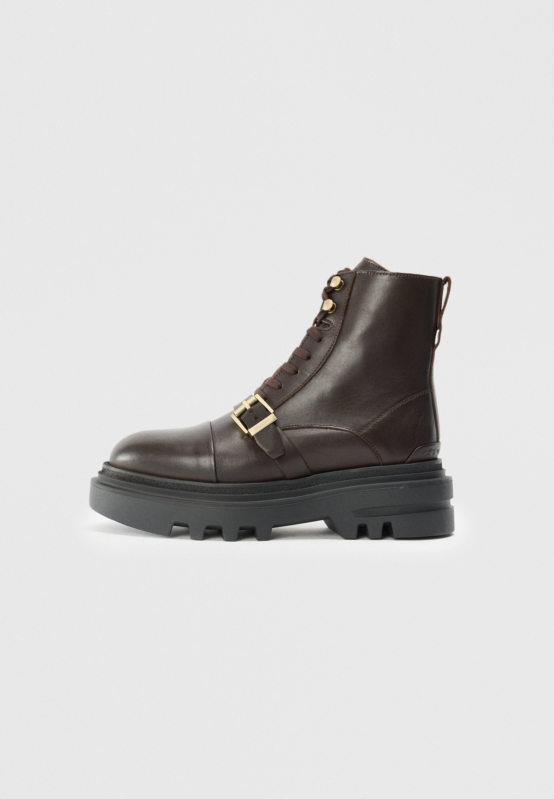 Braune Leder-Stiefelette mit einer massiven schwarzen Sohle, Schnürdesign, goldenen Hardware-Akzenten und einem Riemen mit Schnallen-Detail über dem Mittelfuß.