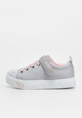 Kindersilberner Glitzersneaker mit pinkfarbenen Akzenten, Herzdesigns auf der Sohle, Klettverschluss und Strasssteinen auf der Zehenkappe.