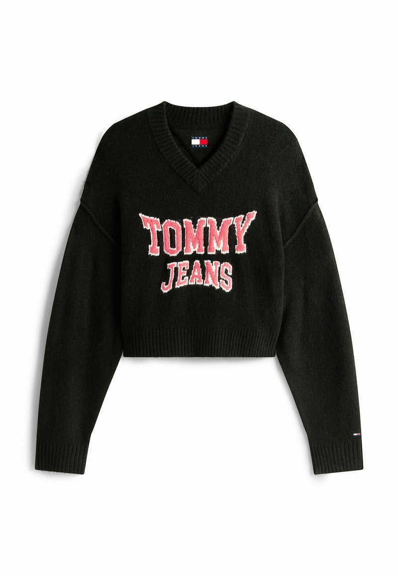Schwarzer, croppter Pullover aus Strickstoff mit V-Ausschnitt, der auf der Vorderseite ein auffälliges, gesticktes "TOMMY JEANS"-Logo in Rot und Weiß präsentiert.