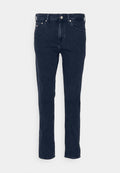 Dunkelblaue Jeans aus Denim mit geradem Schnitt, ausgestattet mit fünf Taschen, einem Gürtelschlaufen und einem Metallknopfverschluss. Glatte Textur, minimalistische Nähte.