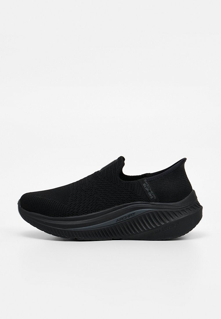 Schwarzer Slip-On-Sneaker mit gestricktem Obermaterial, dicker gepolsterter Sohle und "Arch Fit"-Logo auf der Zwischensohle, entwickelt für Komfort und Unterstützung.
