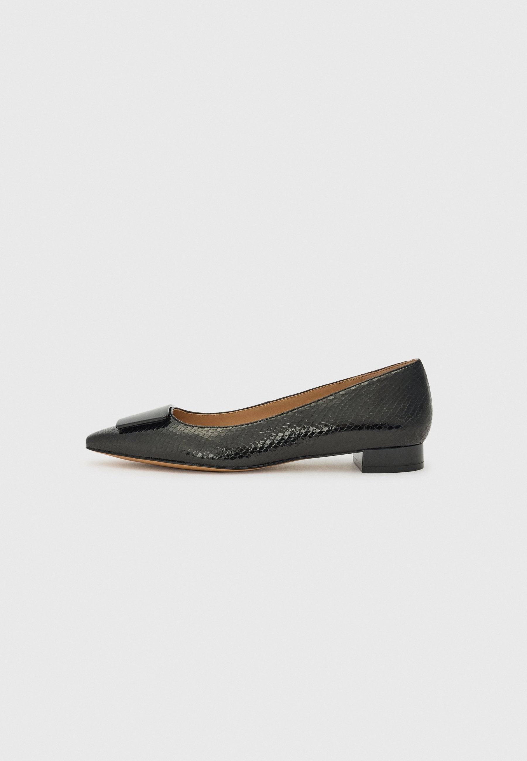 Schwarze flache Schuhe mit spitzem Zehenbereich, strukturiertem Reptilmuster und glänzendem schwarzen Schleifenakzent vorne. Niedriger, blockiger Absatz.