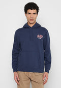 Mann trägt eine marineblaue GAP-Kapuzenjacke mit Vorderfach und beige Hose, steht vor einem einfarbigen hellgrauen Hintergrund.