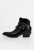 Schwarzer Leder-Stiefelette mit spitzer Zehenpartie, dekorativen Riemen und goldfarbenen Metallakzenten, niedrigem Blockabsatz und glatter Textur.