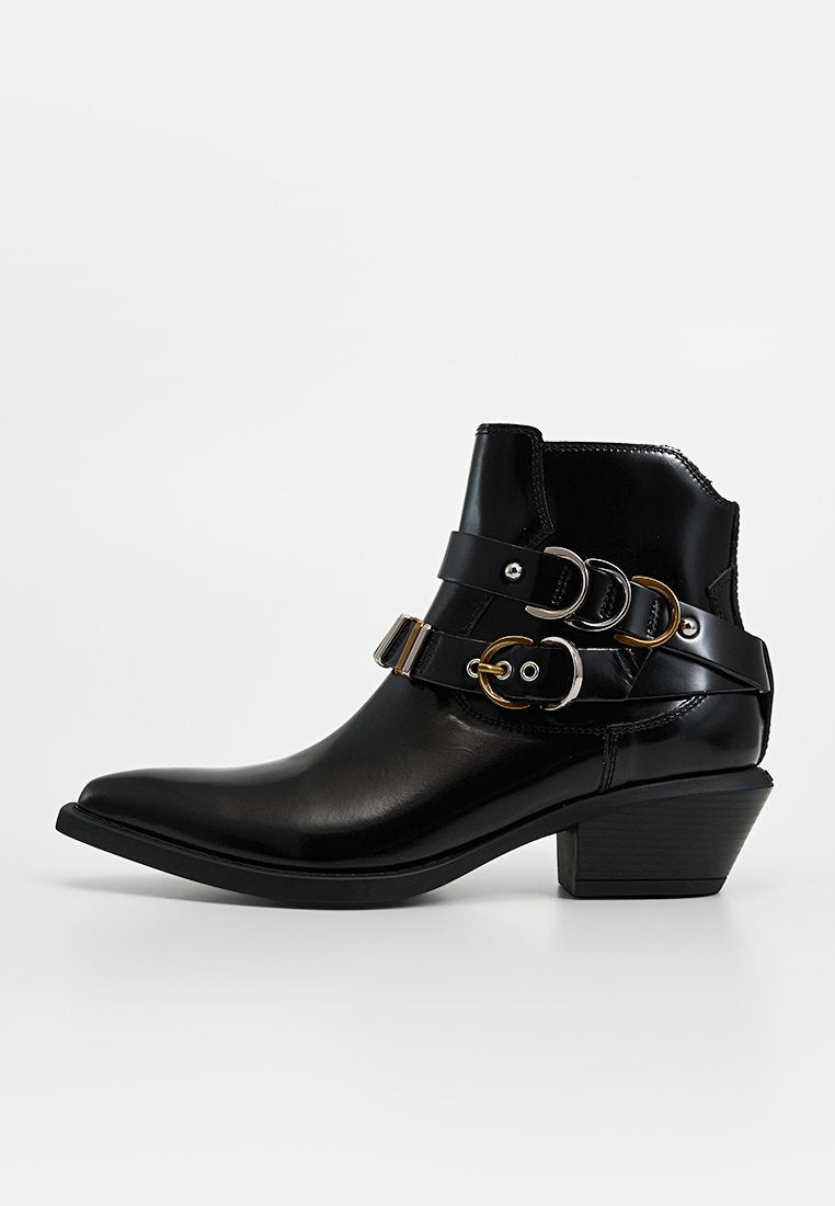 Schwarzer Leder-Stiefelette mit spitzer Zehenpartie, dekorativen Riemen und goldfarbenen Metallakzenten, niedrigem Blockabsatz und glatter Textur.