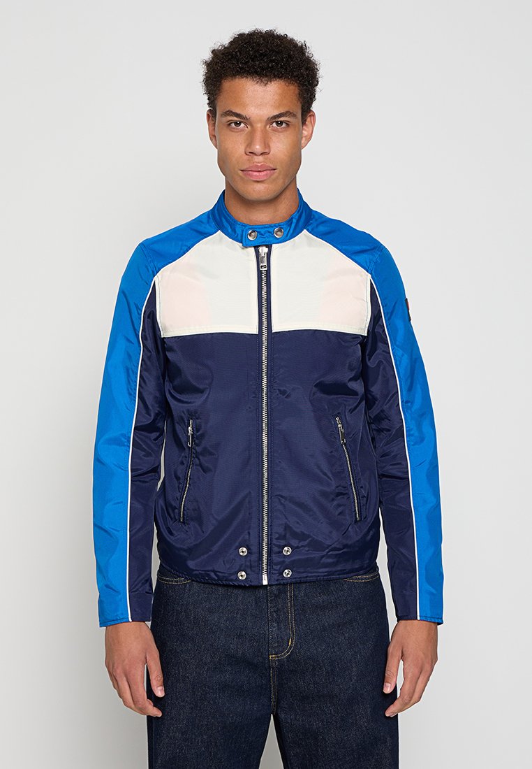 Dunkelblaue und hellblaue Zip-Jacke mit weißen Akzenten, ausgestattet mit einem Stehkragen, zwei vorn mit Reißverschluss verschlossenen Taschen und einer glatten Textur.