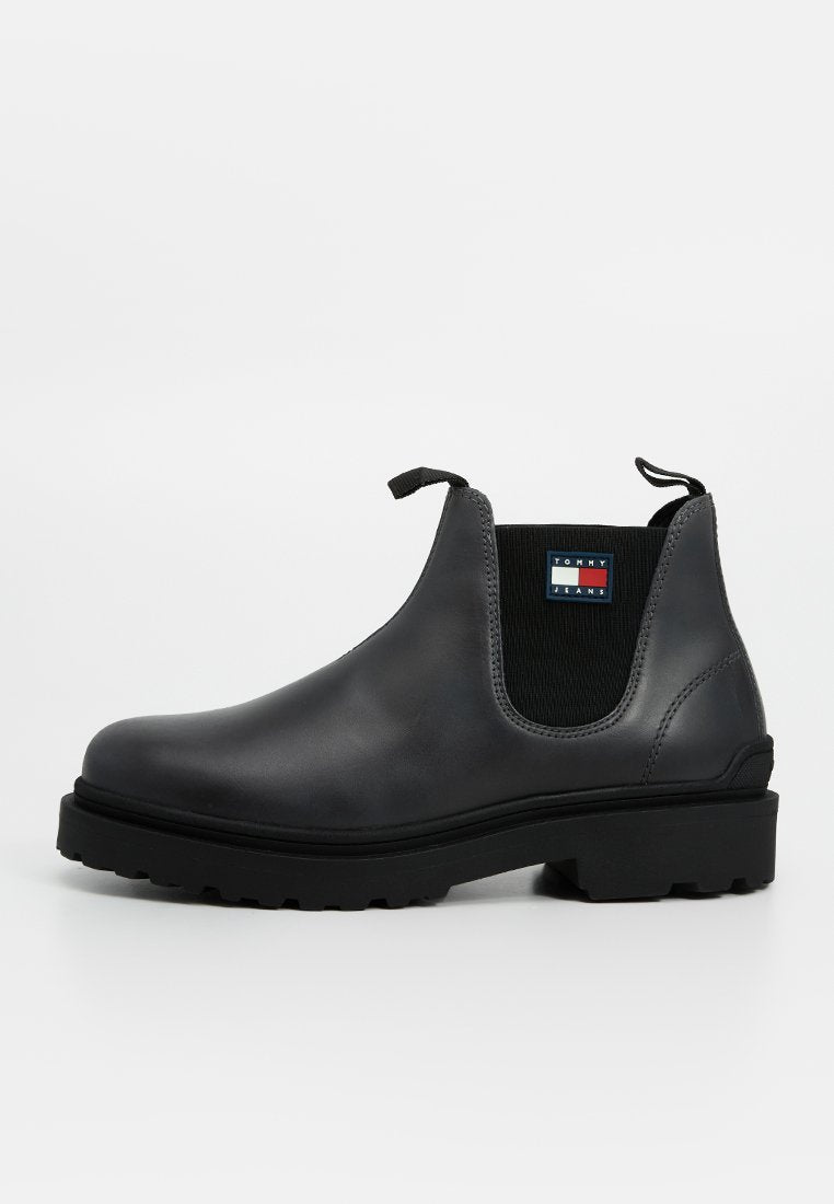 Schwarzer Leder-Stiefel mit elastischen Seitenpanelen, genoppter Sohle und einem Markenpatch an der Seite, im traditionellen Chelsea-Design.