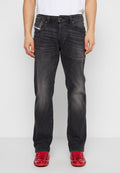 Dunkelgraue Jeans aus Denim mit leichtem Verblassen, mit fünf Taschen und einem Knopfverschluss. Kombiniert mit knallroten Schuhen.